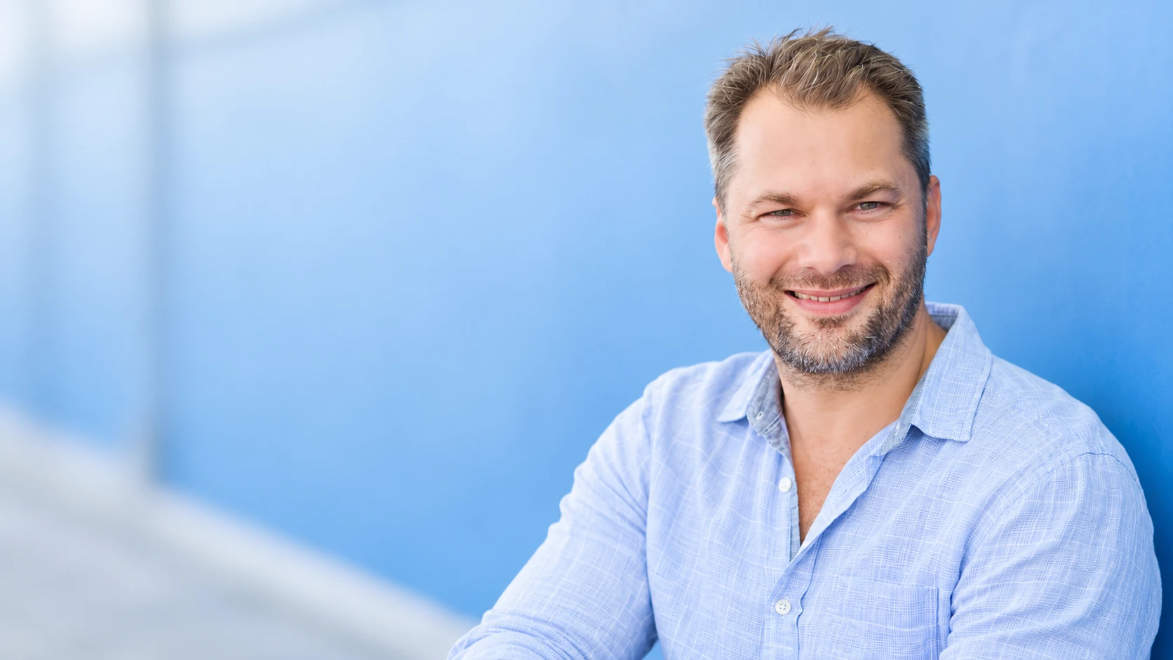 Chris Finn smiling against a softly blurred blue background