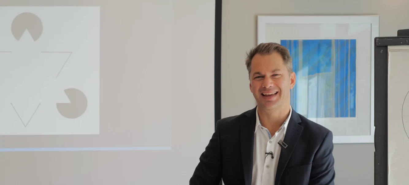 Chris Finn speaking beside a projected presentation and flipchart