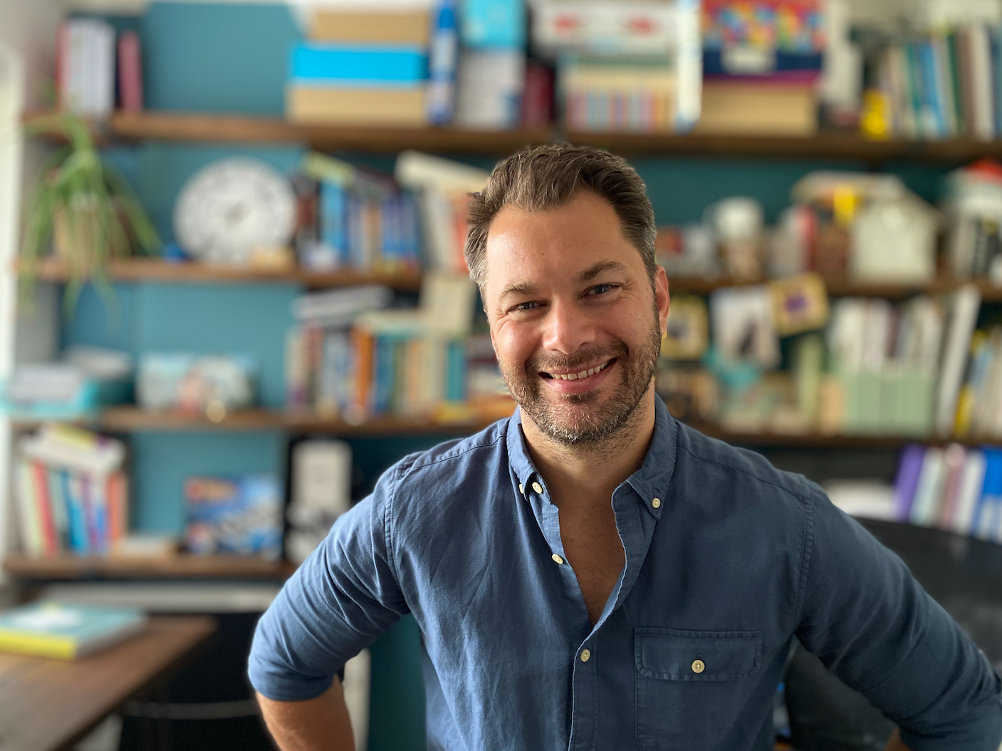 Chris Finn smiling in front of a bookshelf in his office